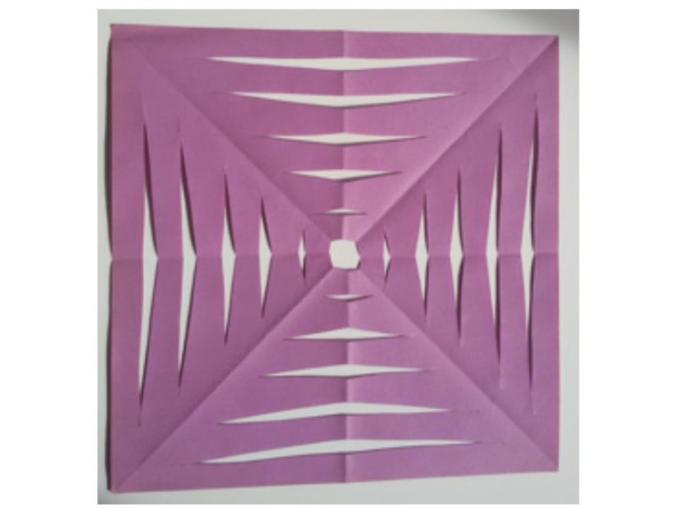 Foto eines Quadrats aus lila Papier, in das ein Muster mit verschiedenen Spiegelachsen geschnitten wurde.